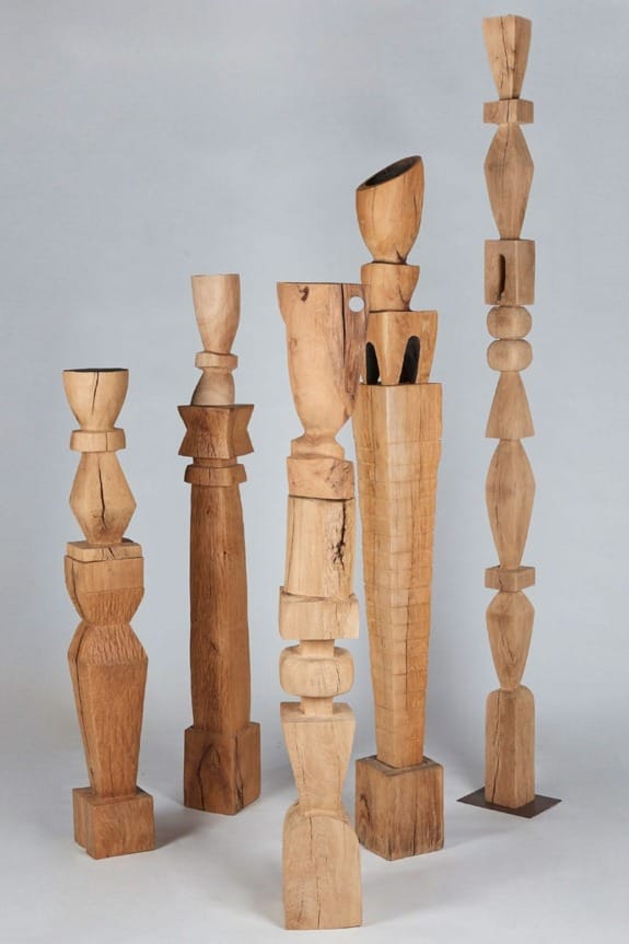 Wooden sculptures of various shapes and heights on a neutral background.