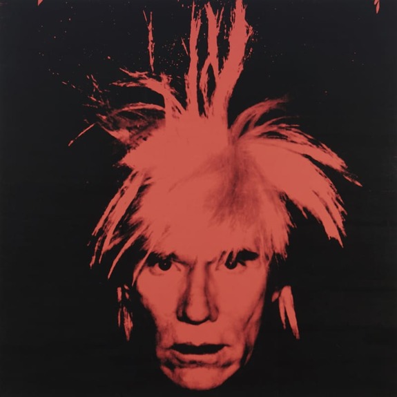 Portrait of a person with distinctive spiky hair against a black background and red overlay, expressing a bold, intense look