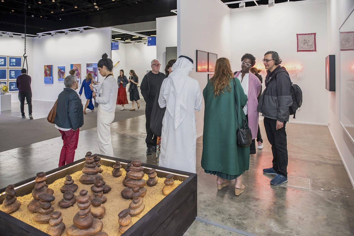 People viewing art in a gallery with sculptures and paintings displayed on white walls.