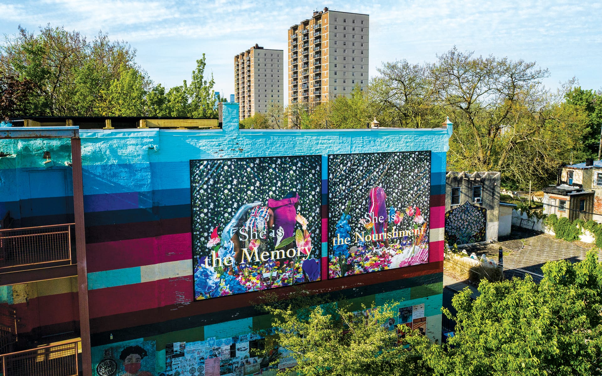 Colorful mural on a building with trees and high-rise apartments in the background.