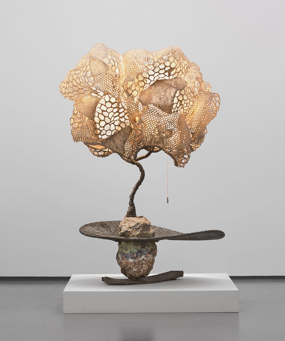 Intricate abstract sculpture with a branching form and organic patterns on a white exhibition pedestal.