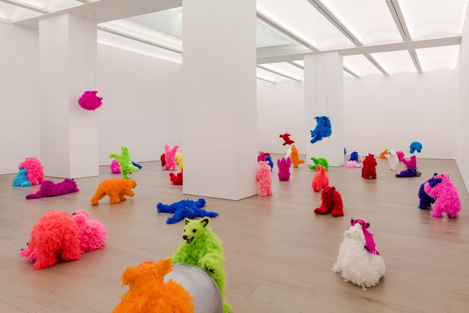 Colorful fuzzy animal sculptures displayed in a modern art gallery.