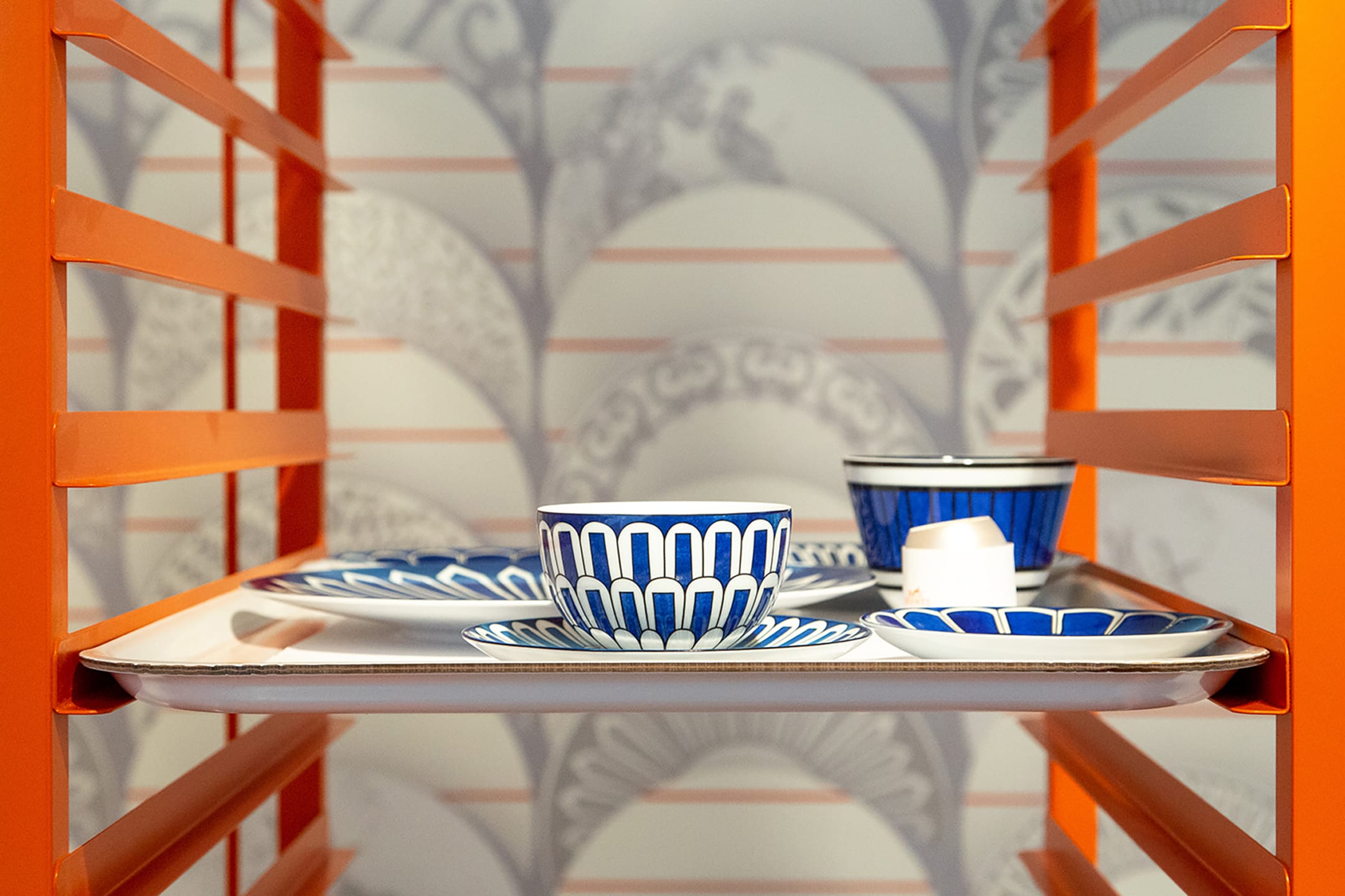 Colorful blue and white dish set on an orange shelf in front of patterned wallpaper.