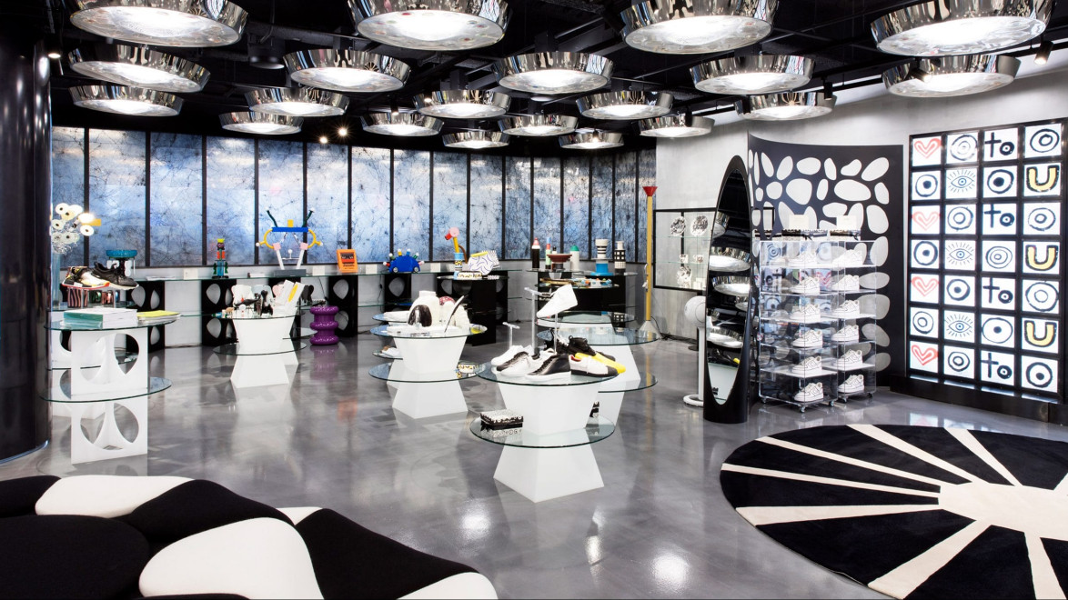Modern shoe store with unique circular displays, abstract patterned rug, and artistic decor elements under stylish lighting.