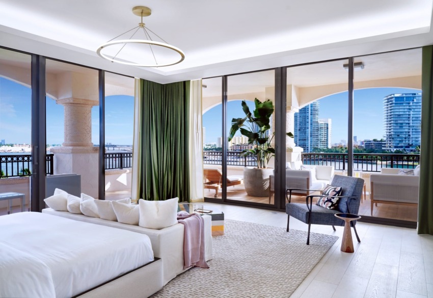Modern bedroom with floor-to-ceiling windows, a cozy bed, green curtains, and a view of the cityscape and balcony.