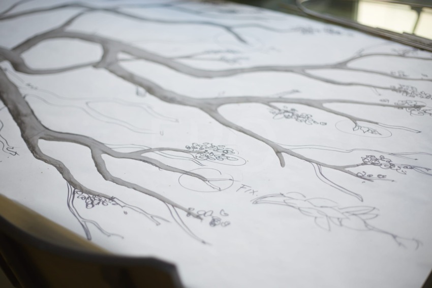 Sketch of tree branches on a white paper sheet with small detailed flowers throughout the drawing.