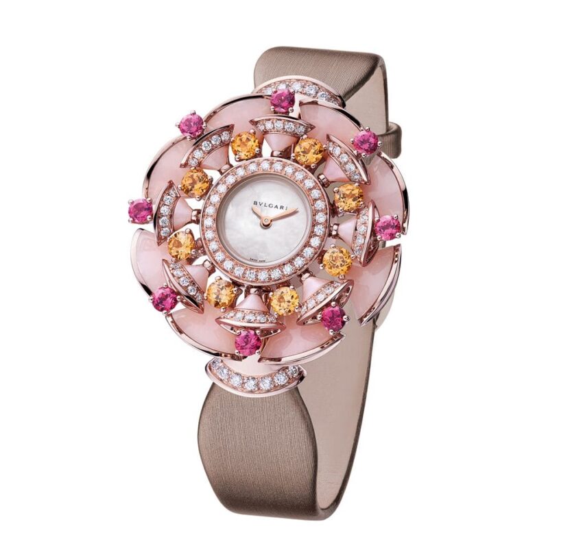 Luxurious rose gold watch with an intricate floral design featuring pink and orange gems on a beige strap.