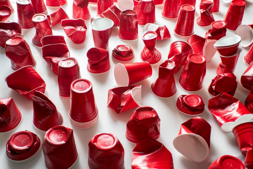 Crumpled red plastic cups scattered on a white surface in bright lighting.