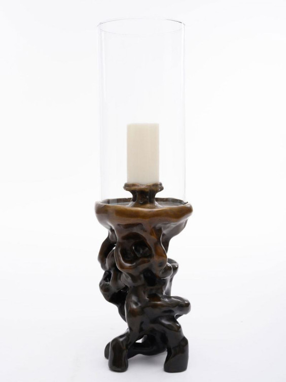 Modern candle holder with a sculptural black base and a tall clear glass cylinder, holding a single white candle.