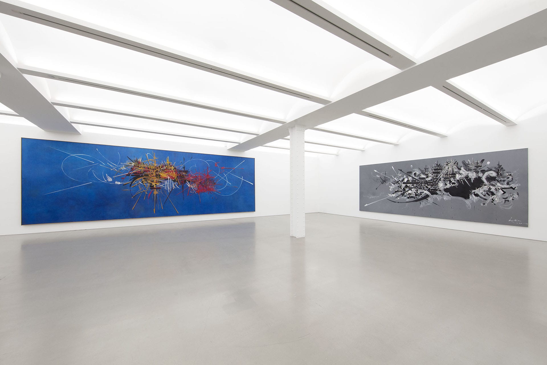 Art gallery with two large abstract paintings on opposing walls, featuring vibrant colors and dynamic designs.