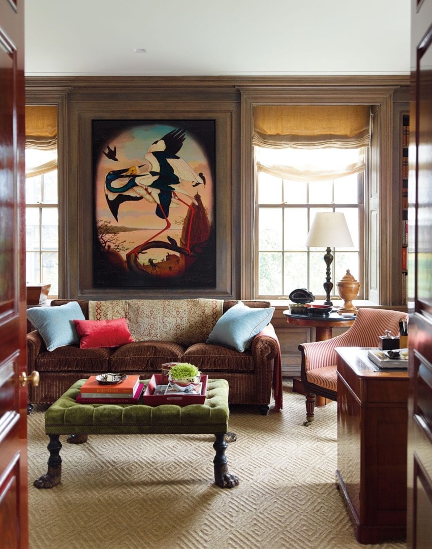 Cozy living room with a brown sofa, colorful cushions, large painting, and window light illuminating the space.