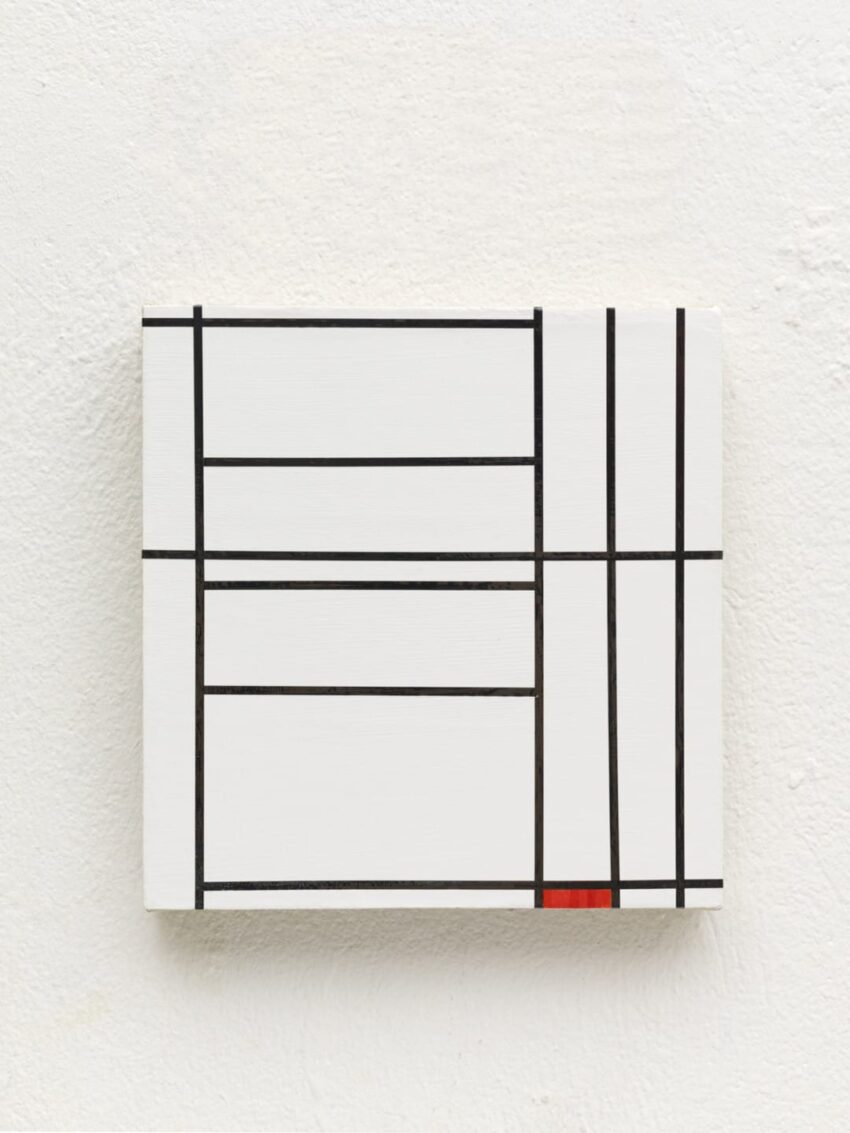 Abstract geometric painting with black lines and red rectangle on white canvas against a textured wall.