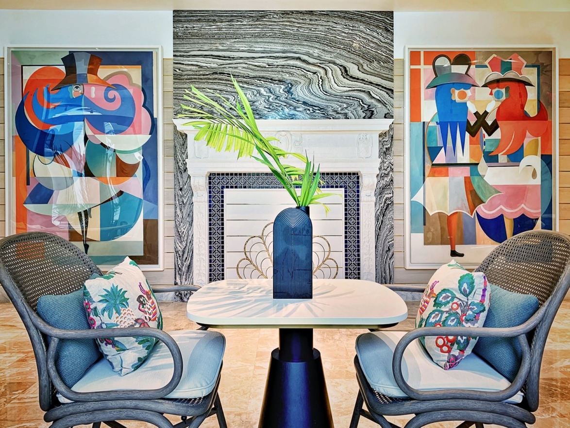 Artistic living room with abstract paintings, modern fireplace, table, and chairs with colorful cushions.