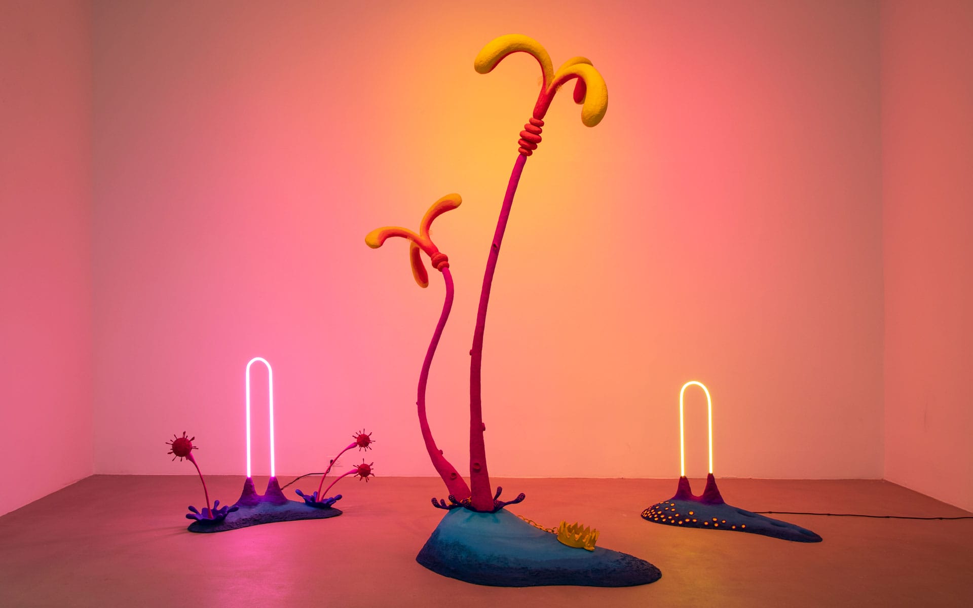 Colorful abstract sculpture with tall, curved stems and neon lights in a minimal gallery space