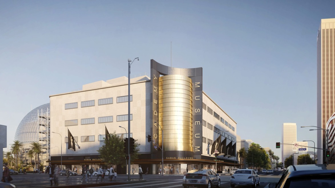 Exterior view of the Academy Museum of Motion Pictures with street traffic and pedestrians under a clear blue sky.