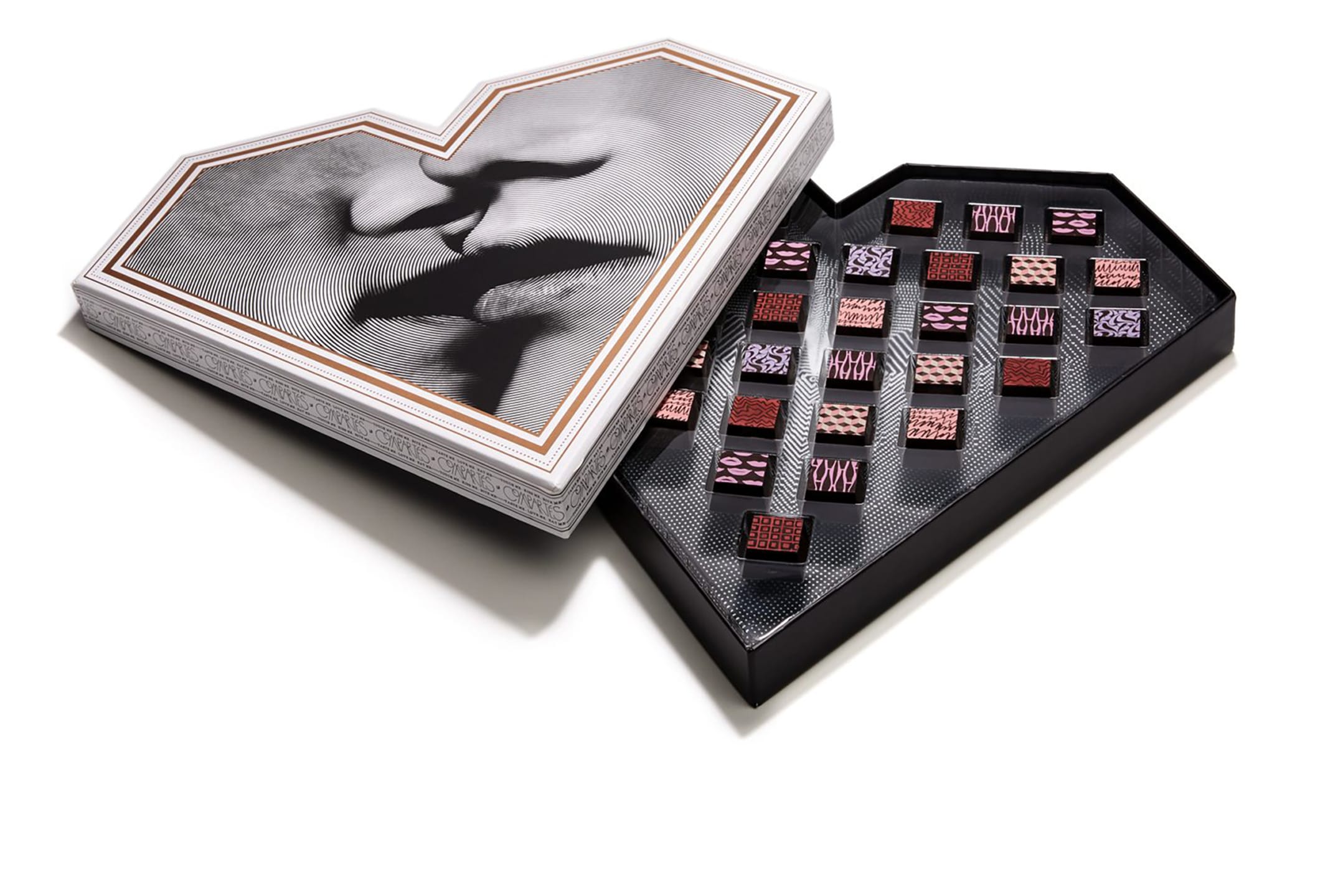 Heart-shaped box of assorted chocolates with artistic designs on each piece, open to reveal chocolate selection.