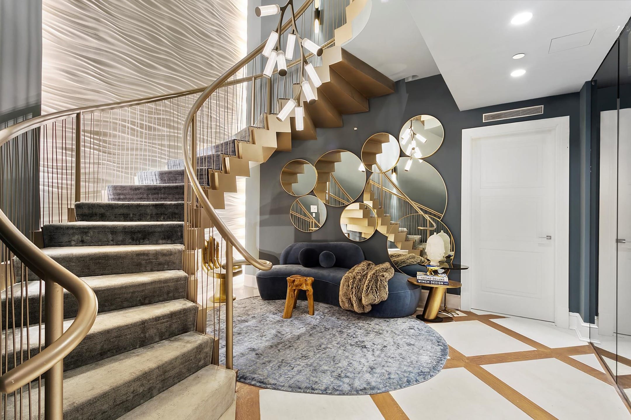 Luxurious modern staircase with round mirrors, plush gray carpet, and stylish seating area with decorative accents.