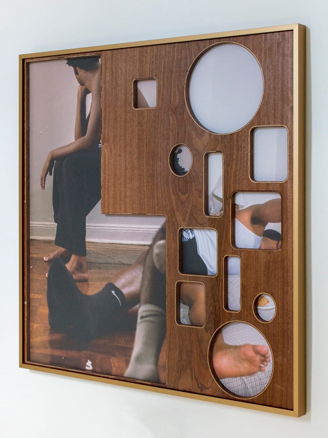 Abstract wooden frame artwork featuring various circular and rectangular cutouts with glimpses of people sitting and resting.