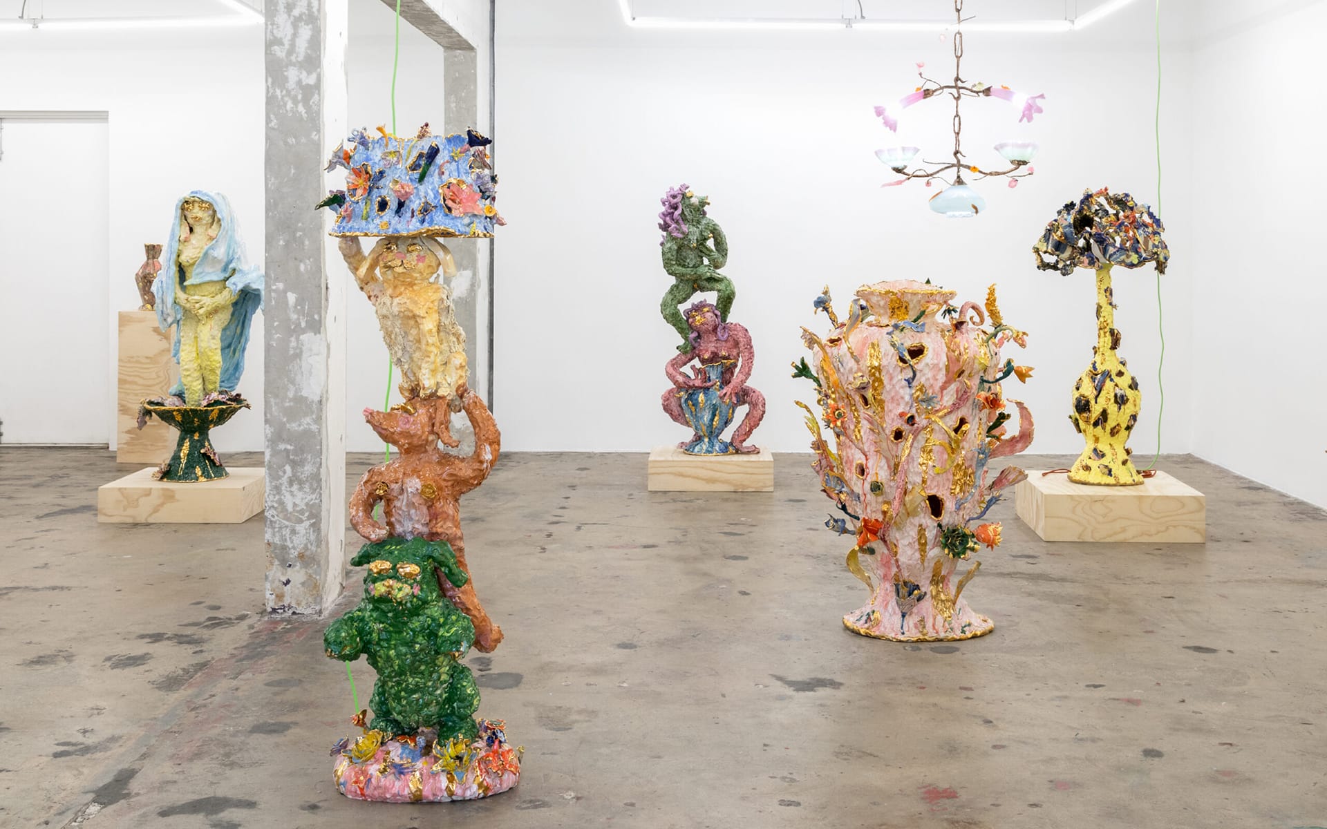 Colorful, abstract sculptures displayed in a modern art gallery setting with a concrete floor and white walls.