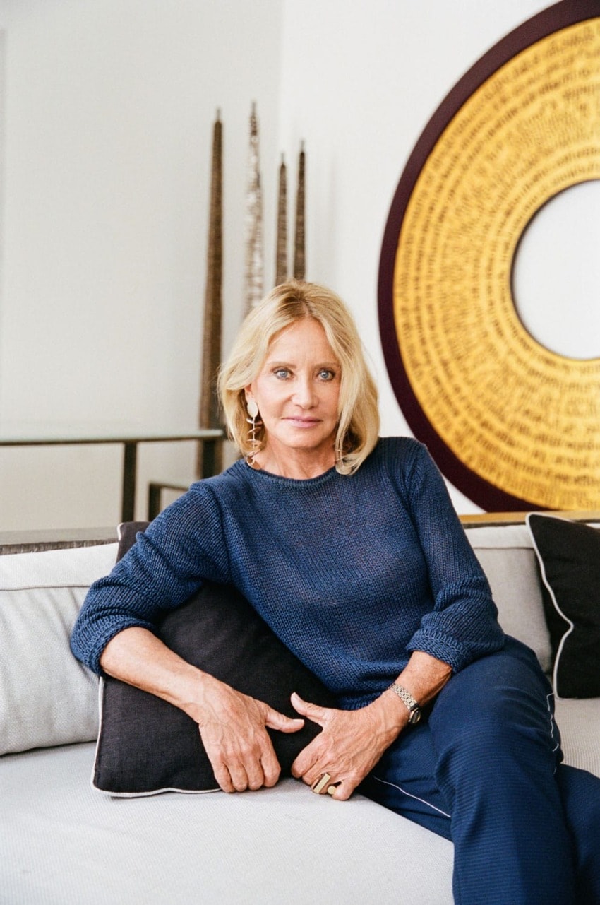 Person sitting on a couch with a blue sweater, large circular art piece in background, and decorative elements around.