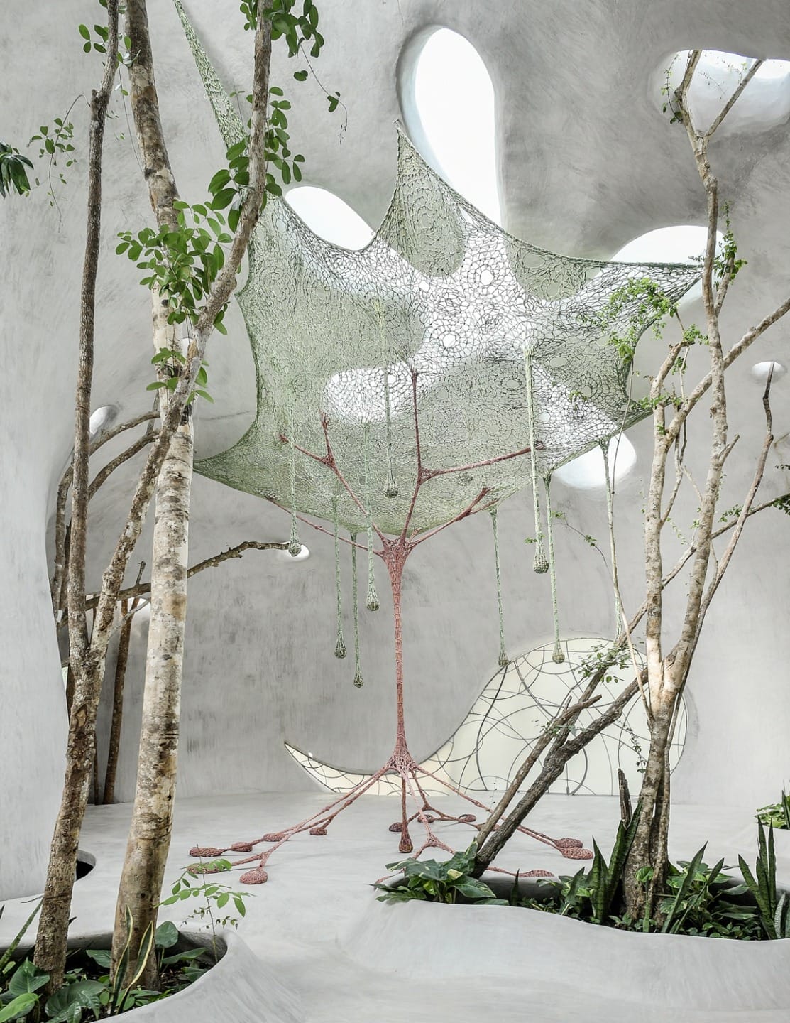 Futuristic architectural space with trees, plants, and a canopy-like structure, featuring soft natural light and organic shapes.