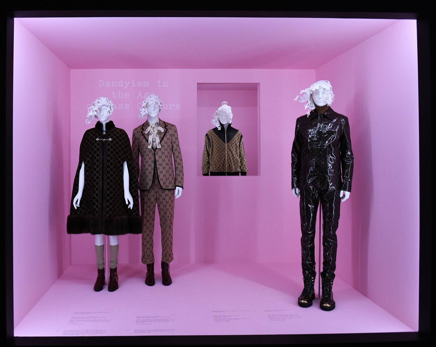 Four mannequins dressed in stylish, contemporary outfits against a pink backdrop with a text about dandyism.