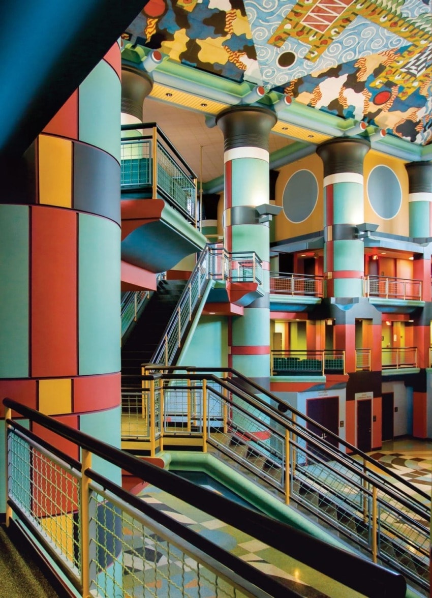 Colorful modern interior with abstract patterns, multilevel stairs, vibrant columns, and geometric ceiling design.