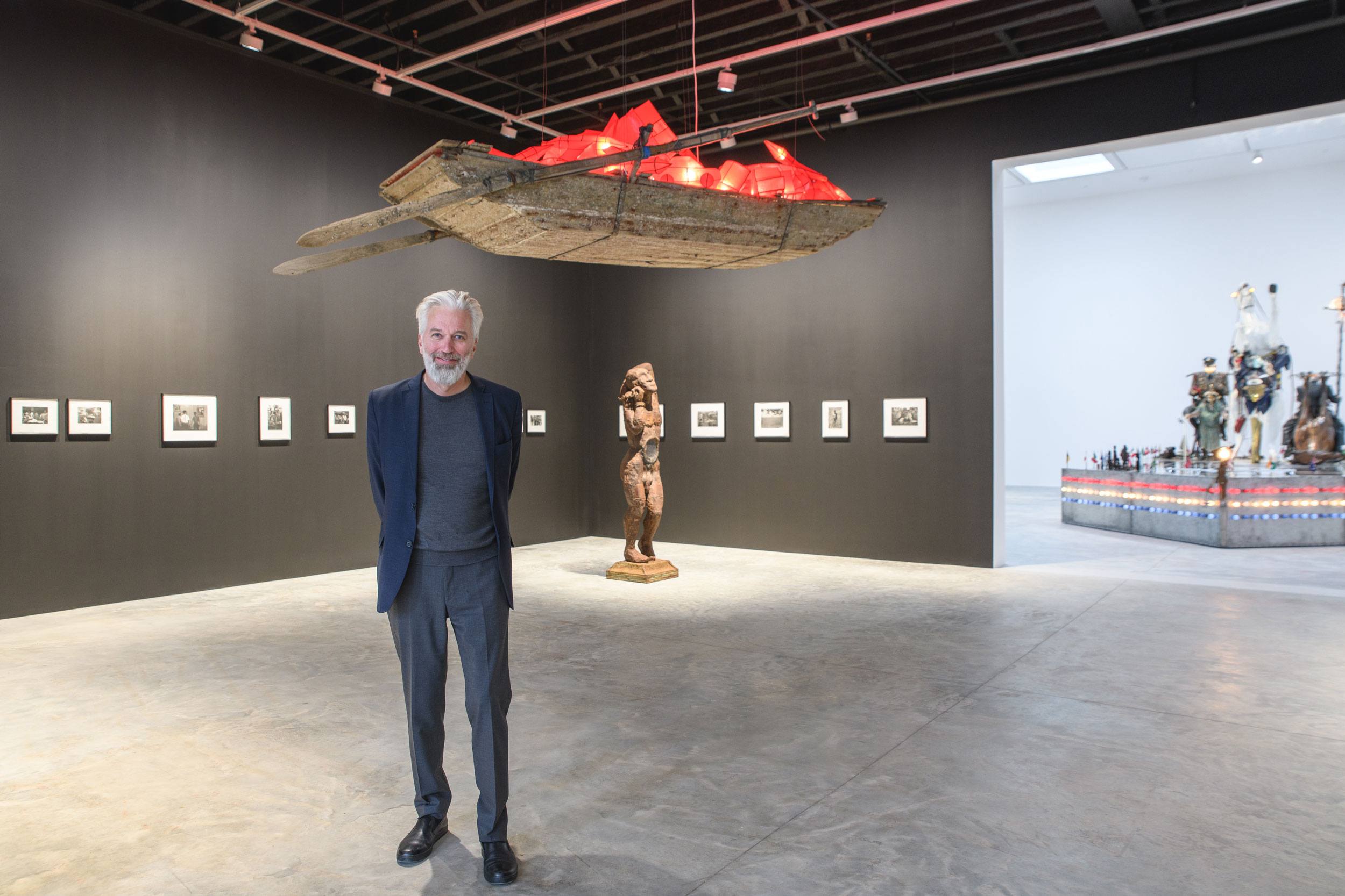 Person standing in modern art gallery with sculptures and framed artworks on display.