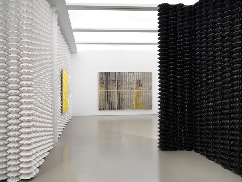 Contemporary art gallery interior with textured black and white walls, large painting, and skylight illuminating the space.