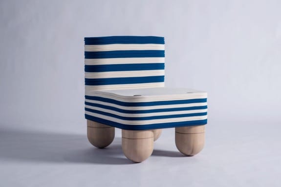 Modern chair with blue and white striped fabric and unique wooden ball legs on a light gray background.