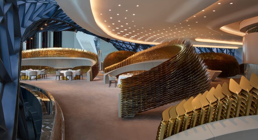 Futuristic restaurant interior with modern architecture, featuring curving golden structures and elegant dining tables.