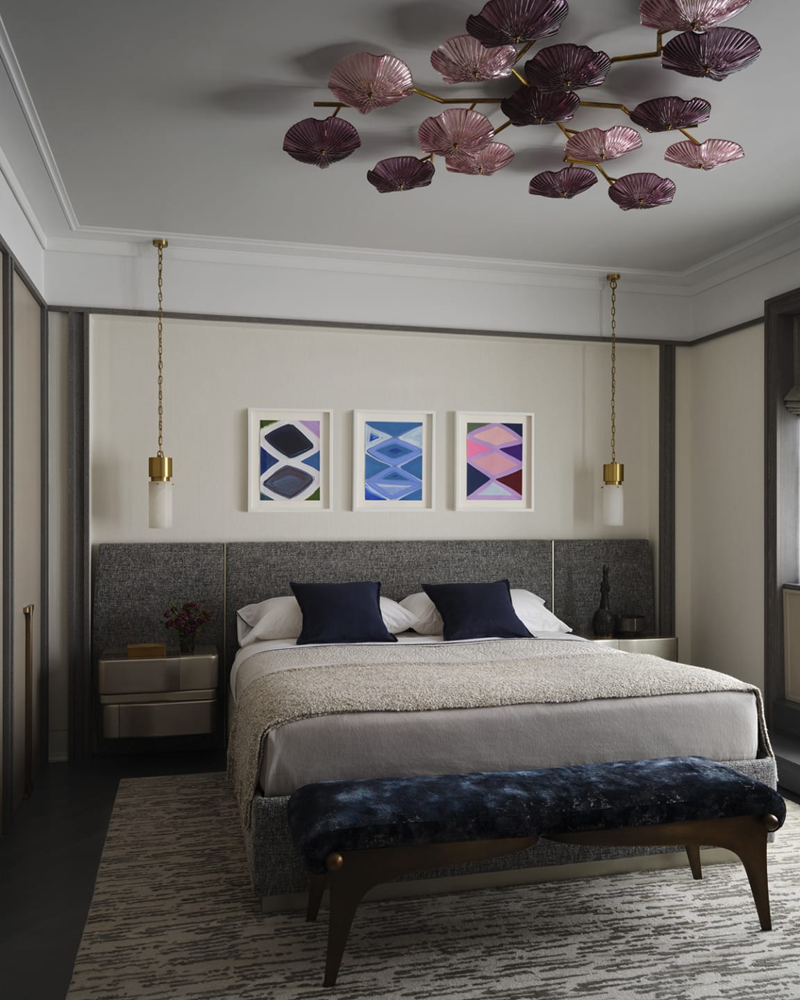 Modern bedroom with a comfortable bed, abstract art, elegant lighting fixtures, and a decorative ceiling feature.