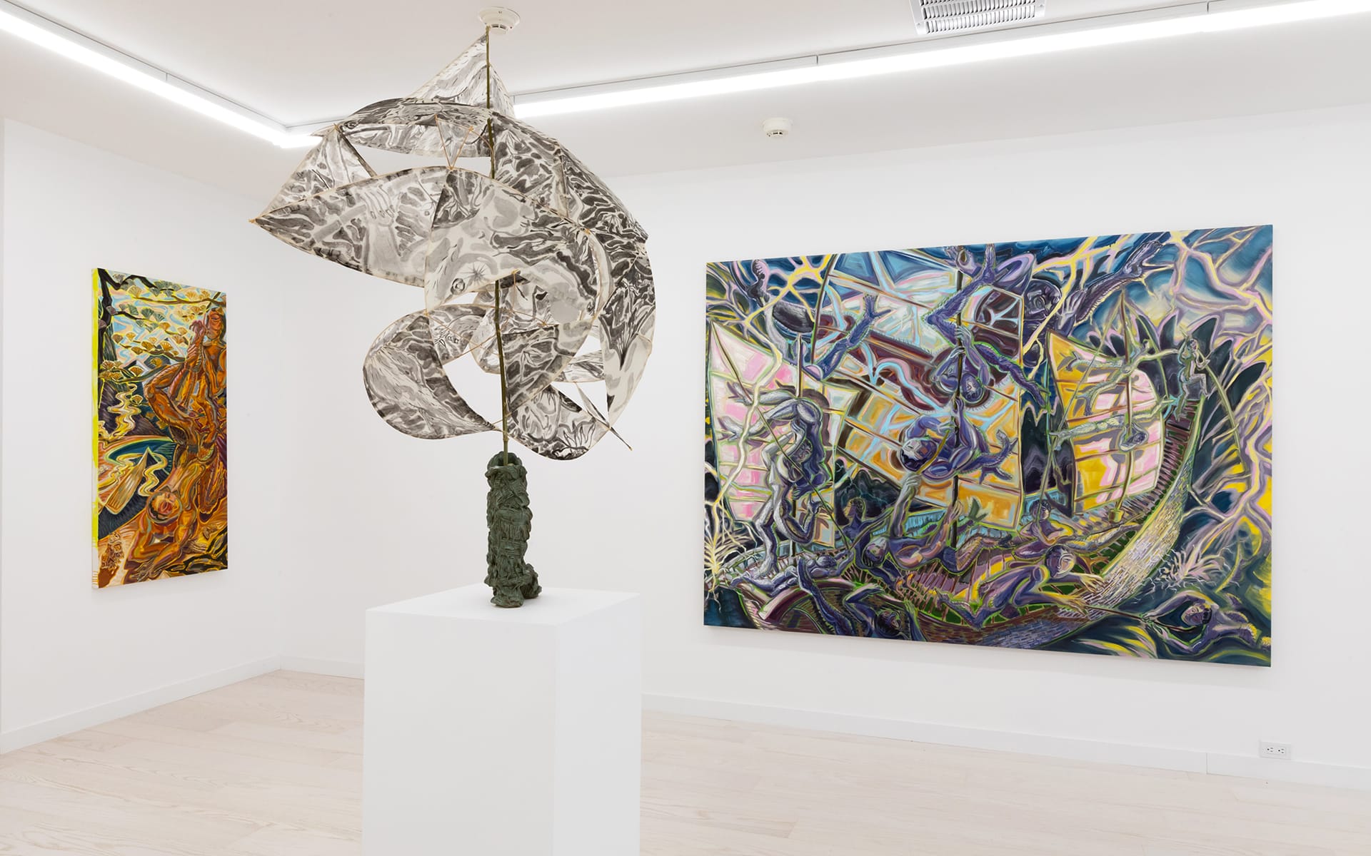 Modern art gallery with abstract metal sculpture and colorful abstract paintings displayed on white walls.