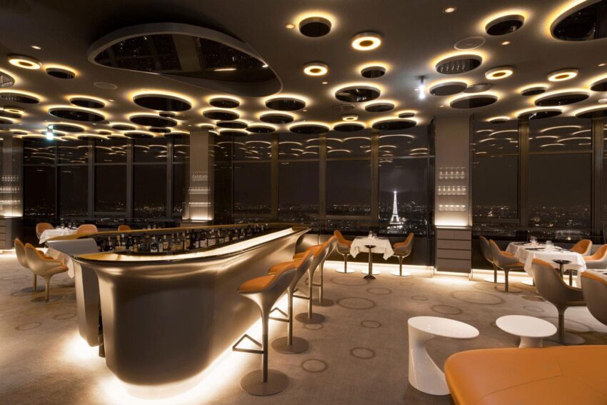 Modern rooftop restaurant interior with stylish furniture, ambient lighting, and panoramic city views at night.