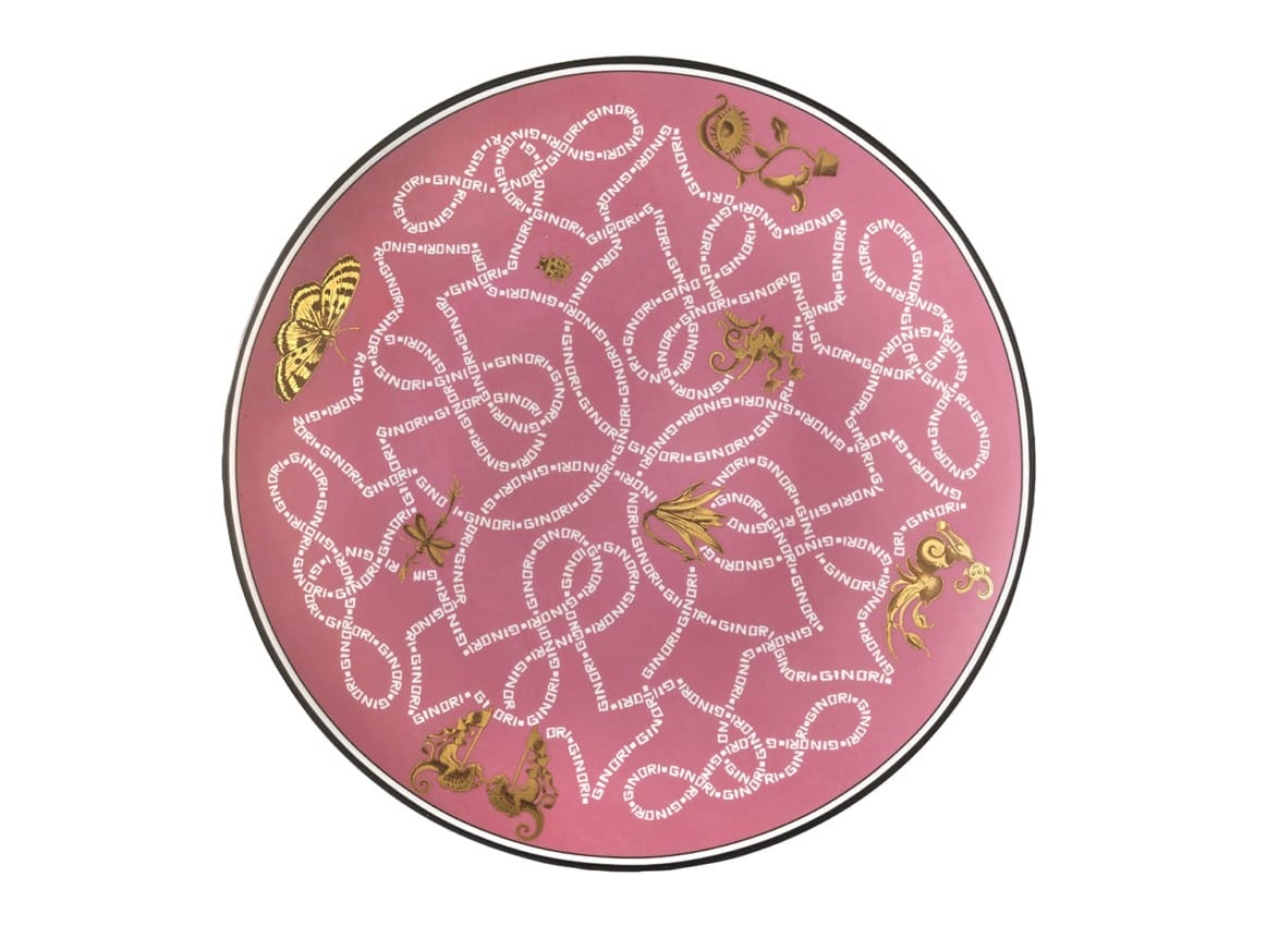 Round pink plate with intricate white patterns and gold floral decorations.