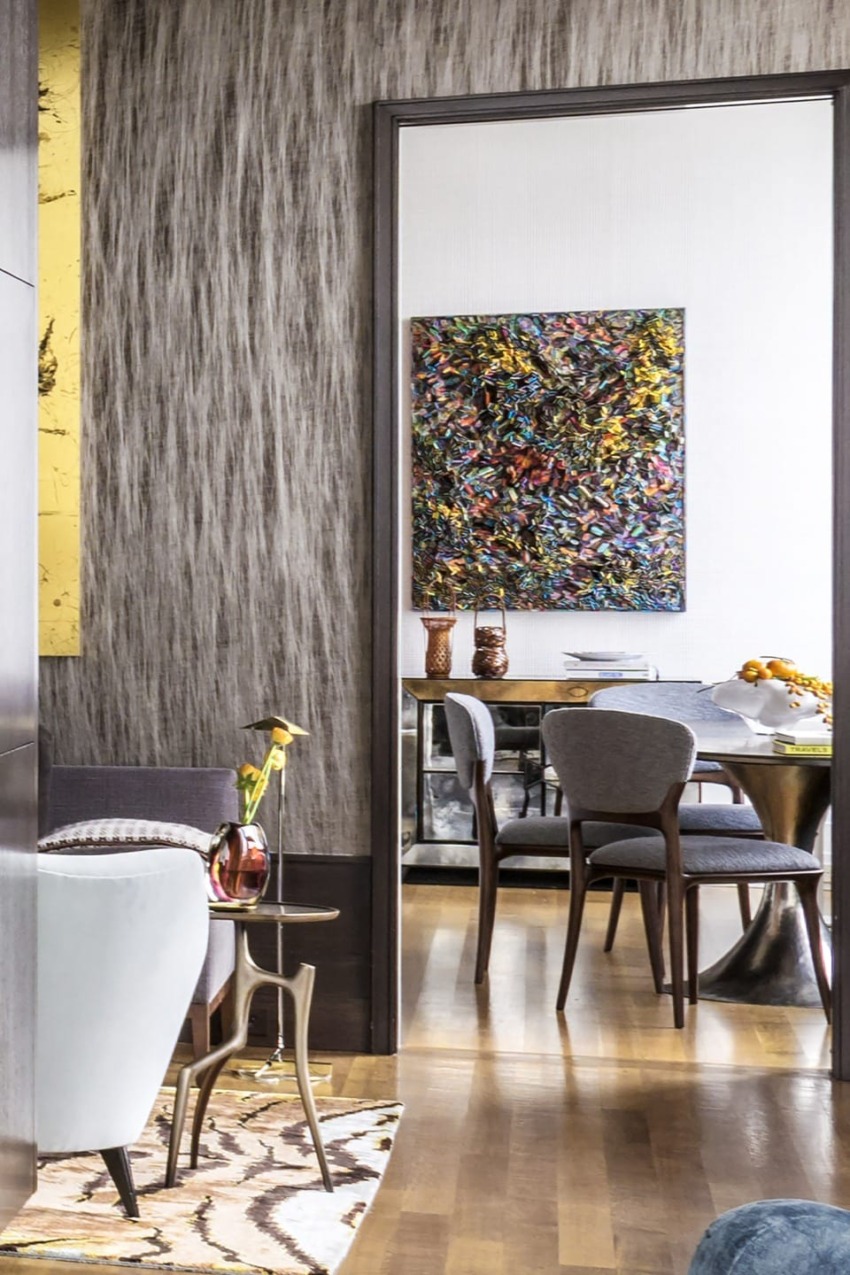Modern living room with textured walls, a colorful abstract painting, mid-century furniture, and a cozy dining area visible.