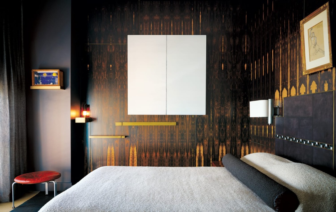 Modern bedroom with dark patterned walls, a large bed, and abstract art on the wall. Cozy, stylish interior design.