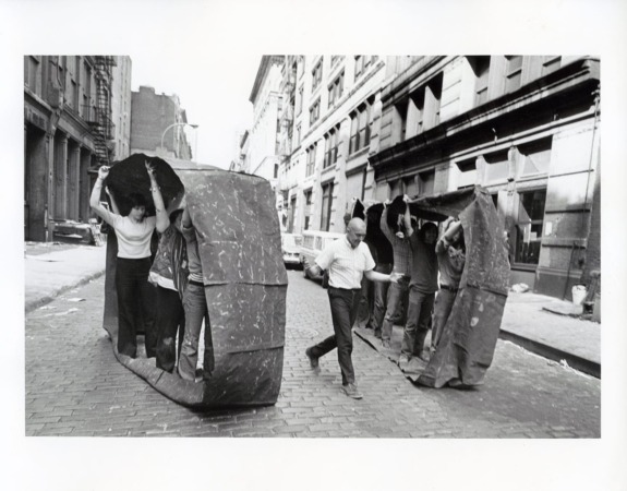People participating in an outdoor group activity, moving under a large fabric tunnel in a city street setting.