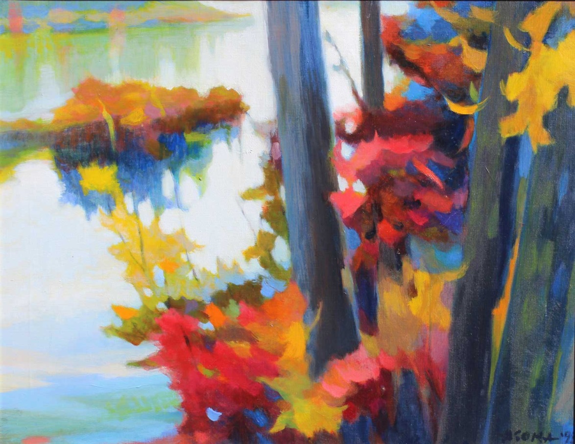 Colorful autumn landscape with red, yellow, and orange foliage by a lake, featuring tall trees and a serene, reflective water.
