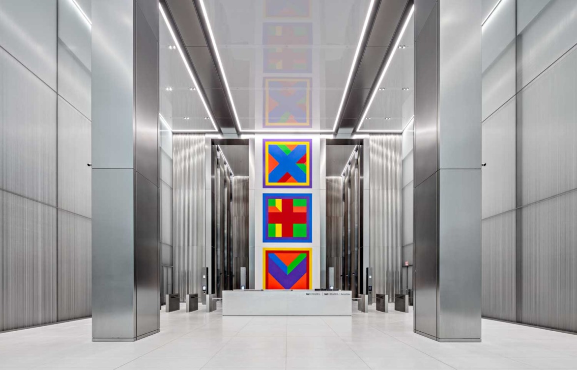 Modern building lobby with tall ceilings and colorful abstract artwork displayed prominently on the wall.