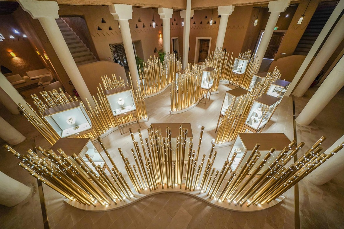 Luxurious jewelry display with golden rods and elegant lighting in a modern showroom with architectural columns.