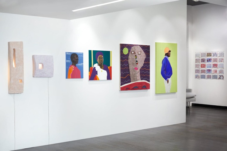 Gallery wall displaying colorful contemporary art pieces, including portraits and abstract designs, in a modern exhibition space.