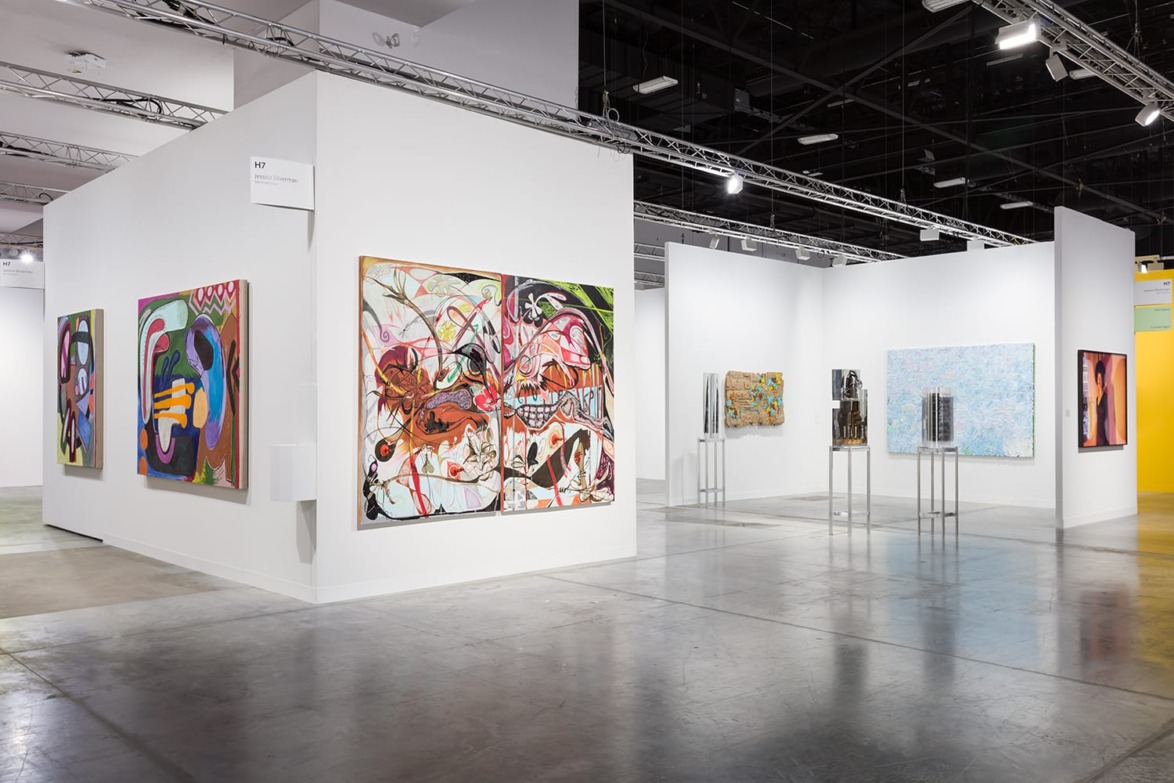 Art gallery interior displaying abstract paintings on white walls under bright overhead lighting.