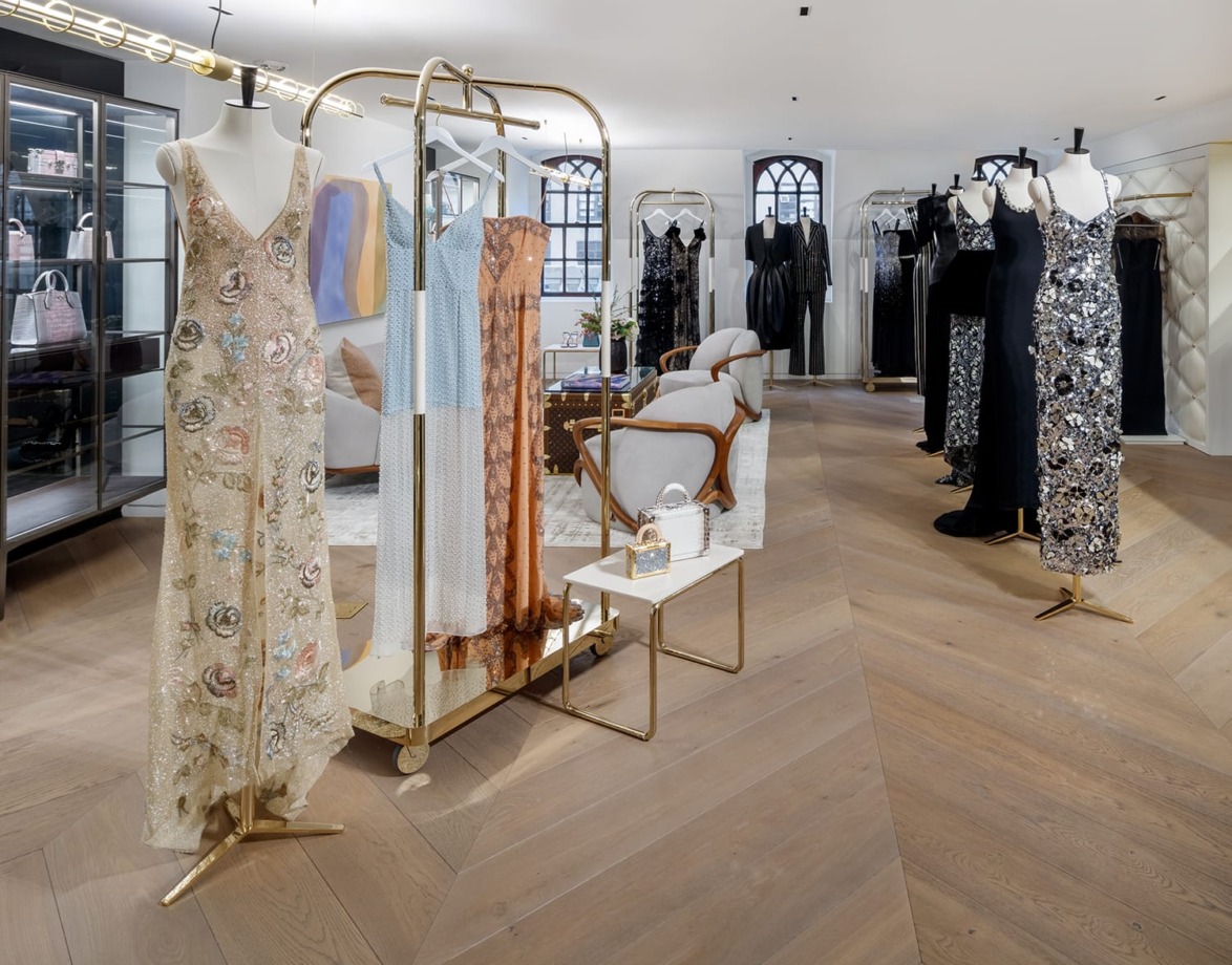 Luxurious fashion showroom with elegant dresses on mannequins, wooden flooring, and modern decor.