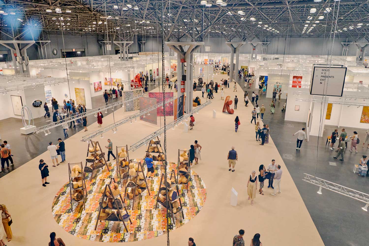 People exploring art installations in a large exhibition hall with various displays and artworks.