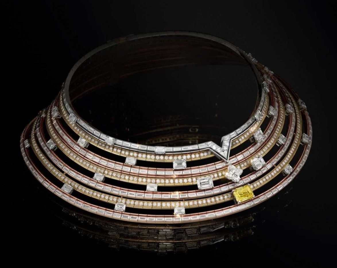 Elegant, multi-layered necklace with diamonds and yellow gemstone on dark background.