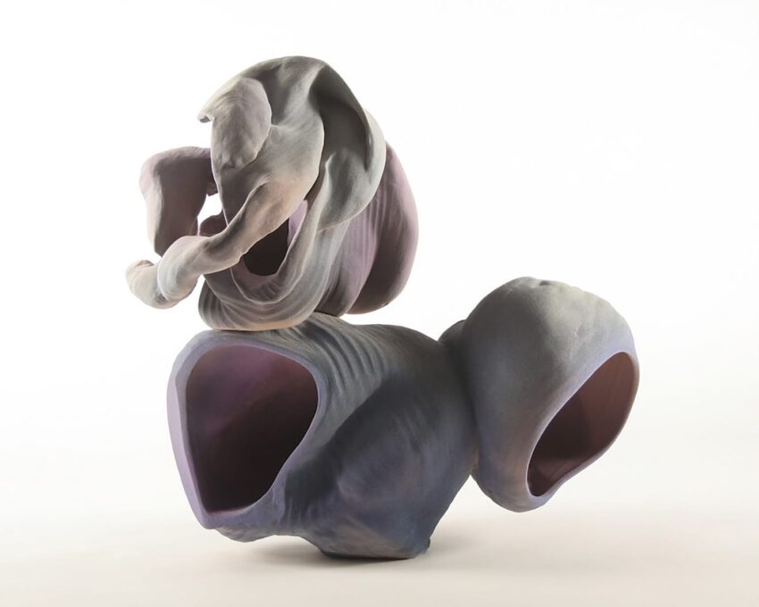 Abstract ceramic sculpture with soft curves and textures in shades of purple and gray on a plain white background.