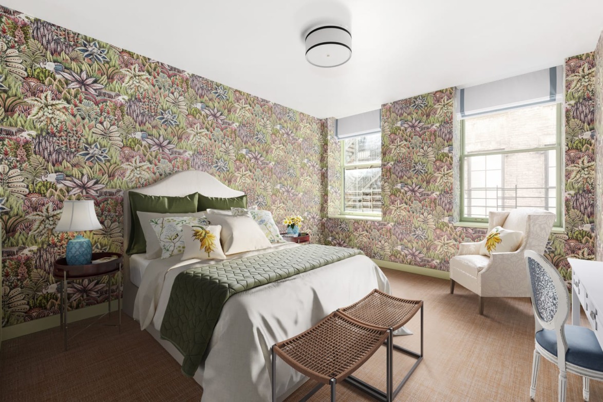 Stylish bedroom with floral wallpaper, bed with green quilt, wicker benches, and light streaming through windows.