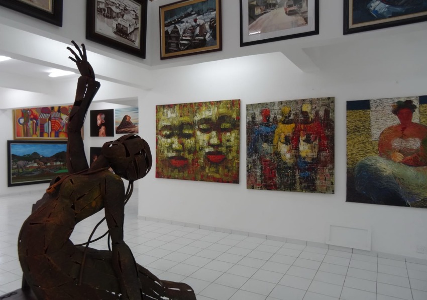 Art gallery with modern sculptures and colorful abstract paintings displayed on white walls and ceiling.