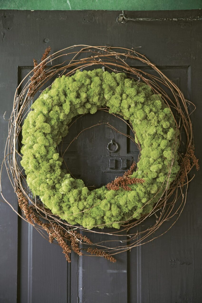 Green moss wreath with branches on a dark wooden door